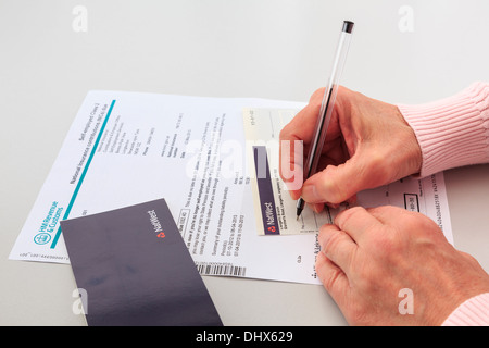 Donna matura la scrittura di un Nat West assegno bancario per pagare una bolletta per i lavoratori autonomi della classe 2 i contributi previdenziali nazionali nel Regno Unito Foto Stock