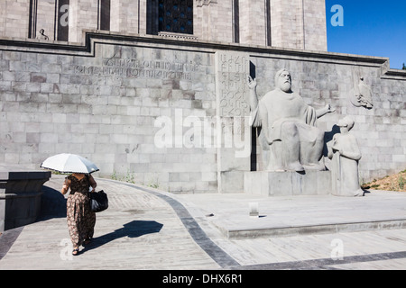 Donna con parasole oltrepassando la Mashtots statua al manoscritto Matenadaran museo. Yerevan, Armenia Foto Stock