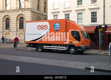 Oxford Oxfordshire, Regno Unito. Ciclista passando una consegna TNT autocarro parcheggiato in Oxford - un 'Zero Emission VEICOLO ELETTRICO" Foto Stock