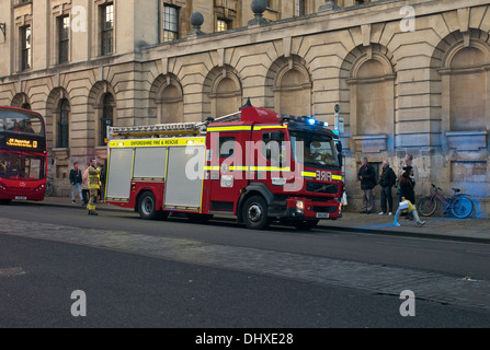 Vigili del fuoco da Oxfordshire Fire & Rescue Service frequentare un incidente sulla strada alta. Pedoni e passeggeri di un autobus watch Foto Stock