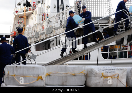 I membri dell'equipaggio a bordo del guardacoste forma vigorosa di una riga verso il basso le taglierine brow, trasferimento di balle di contrabbando verso la taglierina per il molo durante un farmaco offload a Port Everglades, Fla., nov. 15, 2013. Questi interdictions sono state effettuate come parte Foto Stock