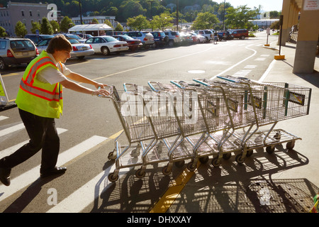 L'uomo wheeling carrelli di shopping Foto Stock