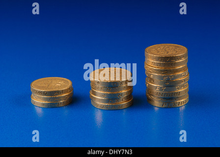 Ordine crescente di pile di monete su sfondo blu Foto Stock