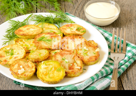 Zucchine fritte con aneto e aglio sul tavolo di legno Foto Stock