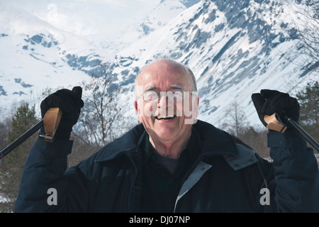 Senior uomo sorridente con aumentata bastoncini da sci mentre lo sci nordico attraverso la valle glaciale del ghiacciaio Nigardsbreen, Norvegia Foto Stock