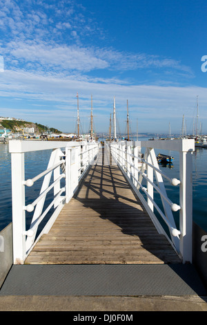 Bianco pontile in legno la passerella che porta a marina con cielo blu e nuvole Foto Stock