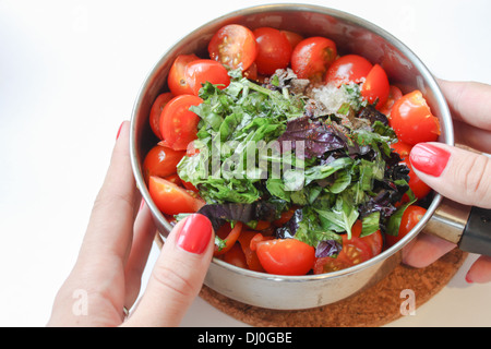 Mani tenendo la pentola con gli ingredienti per cucinare [salsa di pomodoro] [ricetta salsa] su sfondo bianco Foto Stock