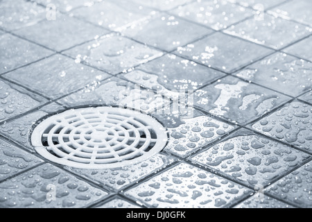 Scarico a pavimento, eseguendo l'acqua nella doccia, oscurata immagine in bianco e nero Foto Stock