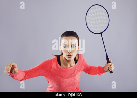 Ritratto di giovane donna sport giocando badminton contro uno sfondo grigio. Montare atleta giocando badminton. Foto Stock