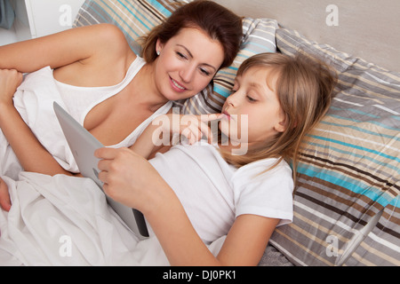 Madre e figlia sul letto con ipad Foto Stock