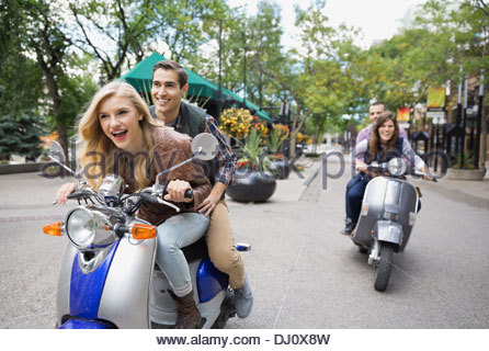 Due coppie in sella scooter sulla strada di città