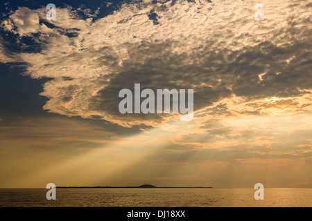 Doccia oro dei raggi del sole che passa a 45 gradi attraverso la coltre di nubi scure al tramonto su isole Gili in Indonesia Foto Stock