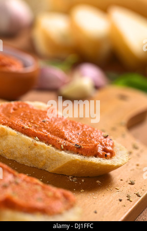 In casa pomodoro-burro spalmato su fette di baguette con pepe macinato fresco sulla tavola di legno Foto Stock