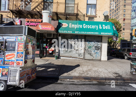 Parcheggiato hot dog carrello, Dunkin Donuts e chiuso deli nel quartiere di Chelsea di New York Foto Stock