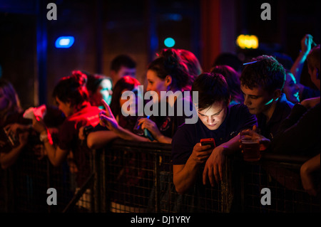 Un giovane uomo di controllare il suo telefono come Welsh studenti universitari parte all'annuale inter-College gig, Aberystwyth University, 2013 Foto Stock