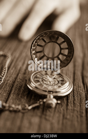 Un orologio da tasca su uno sfondo di legno e la mano. Foto Stock