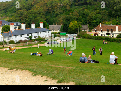 Gli adolescenti in gita scolastica sfogarsi da somersaulting discesa da una collina in Lulworth Cove, Dorset Foto Stock