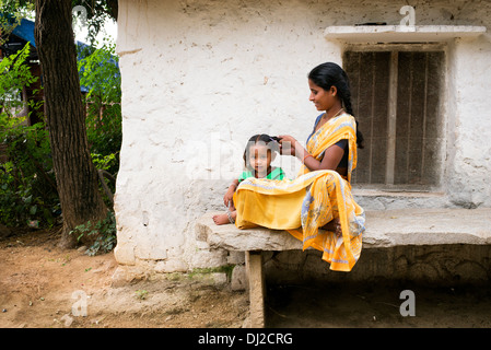 Madre indiana la sua pettinatura giovani figlie i capelli in una zona rurale villaggio indiano. Andhra Pradesh, India Foto Stock