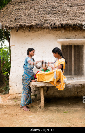 Madre indiana e pettinare i suoi giovani figlie i capelli in una zona rurale villaggio indiano. Andhra Pradesh, India Foto Stock