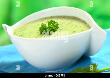 Crema di spinaci minestra guarnita con prezzemolo (messa a fuoco selettiva, messa a fuoco sulla parte anteriore del prezzemolo) Foto Stock