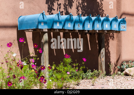 Una fila di cassette postali turchese sorge di fronte a un muro di adobe su Garcia San a Santa Fe, New Mexico. Foto Stock