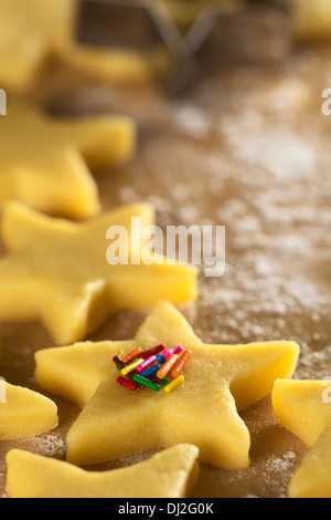 Crudi a forma di stella i biscotti con zucchero colorato spruzza su infarinato e superficie in legno (messa a fuoco selettiva) Foto Stock