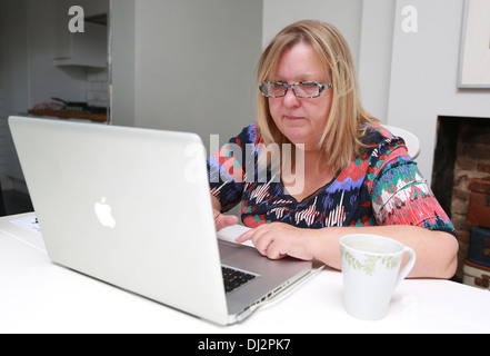 Il sovrappeso donna di mezza età con occhiali che usano internet. Foto Stock