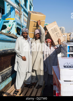 Gli uomini carichi di caricamento sul Dhow alla banchina di carico sul Creek di Dubai Emirati Arabi Uniti Foto Stock