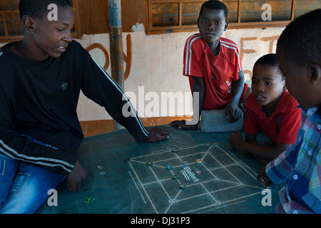 I bambini giocano con impiallacciature in un villaggio vicino al camp Khwai River Lodge da Orient Express in Botswana, entro la Moremi Game Foto Stock