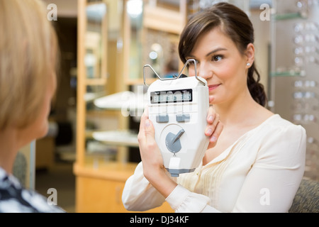 All'ottico optometrista che mostra Pupilometer per donna matura Foto Stock