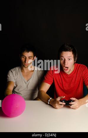 Guy completamente annoiato a suoi amici entusiasti per i videogiochi Foto Stock