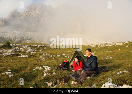 Giovani camping in montagna nella nebbia e godersi il tramonto Foto Stock