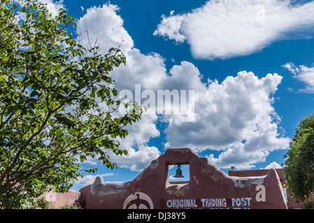 Dettaglio della parte superiore della facciata anteriore originale del Trading Post di Taos, Nuovo Messico con campana in adobe e parete di cielo blu. Foto Stock