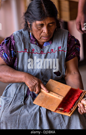 Un zapoteco donna indigena mano carte lana tinti in filo per essere utilizzati nella tessitura tappeti tradizionali in Teotitlan de Valle, Messico Foto Stock