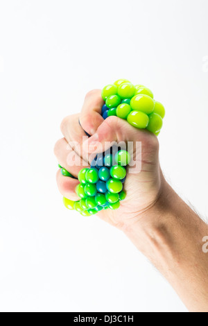 Maschio di spremitura a mano palla su sfondo semplice Foto Stock