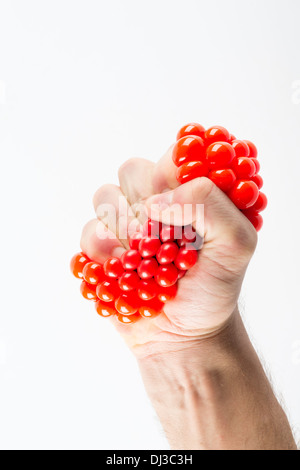 Maschio di spremitura a mano palla su sfondo semplice Foto Stock