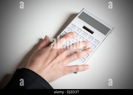 Immagine di una mano femminile digitando su una calcolatrice di bianco con display vuoto Foto Stock