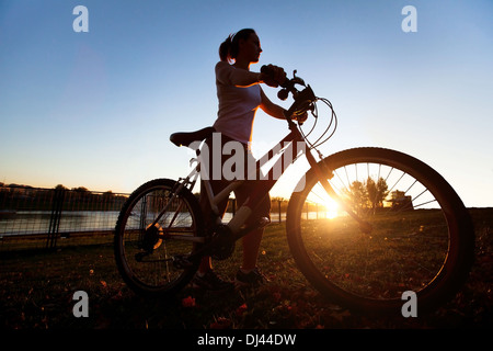 Silhouette di donna giovane con bicicletta outdoor Foto Stock