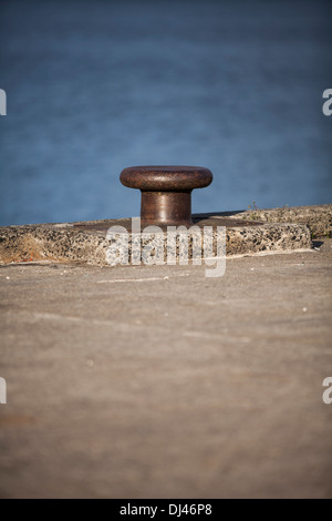 Un vecchio bollard marino alla fine di un molo. Foto Stock