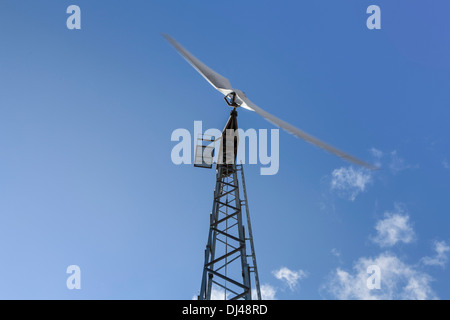 Turbina eolica contro un luminoso cielo blu su una farm. Foto Stock