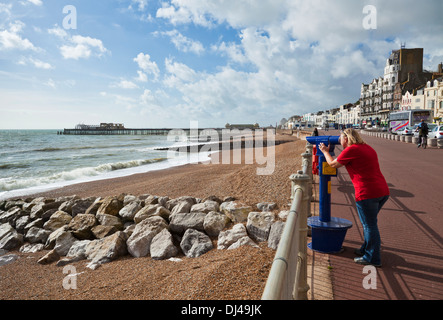 Persona che guarda attraverso un telescopio sulla passeggiata a Hastings verso il molo Hastings lungomare East Sussex UK GB Europa Foto Stock