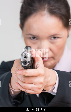 Close up ritratto di donna in business suit puntando una pistola a mano a voi Foto Stock