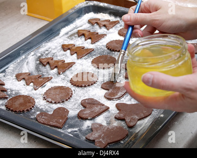 Natale gingerbread cookies tagliato fuori dalla pasticceria grezzo spazzolato con albume di uovo di gallina Foto Stock