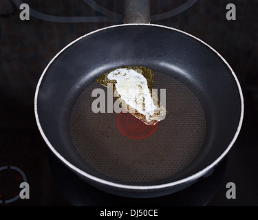 Piccolo pezzo di burro di latteria fusione su padella calda sul coocker elettrico Foto Stock