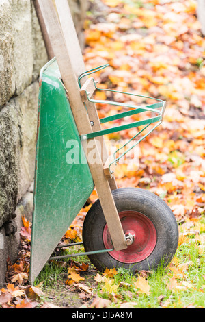 Carriola in giardino con foglie di autunno in background Foto Stock