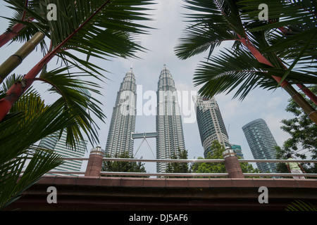 Petronas Towers in Kuala Lumpur salire verso il cielo tra le palme da giardini sotto in ottobre 2013. Foto Stock