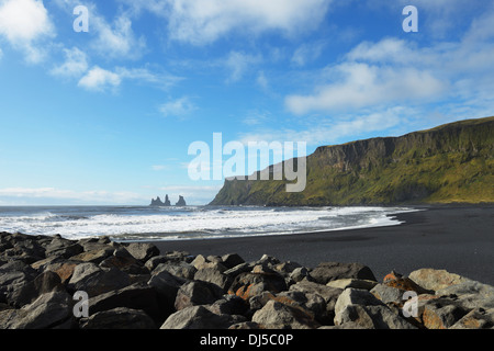 Lava nera Beach con il basalto di pile di Reynisdrangar in background; Vik, Vestur-Skaftafellssysla, Islanda Foto Stock