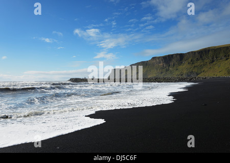Lava nera Beach con il basalto di pile di Reynisdrangar in background; Vik, Vestur-Skaftafellssysla, Islanda Foto Stock