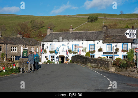 Persone turisti escursionisti visitatori a piedi da Blue Bell Inn Village pub in inverno Kettlewell Wharfedale Yorkshire Dales National Park Inghilterra Regno Unito Foto Stock