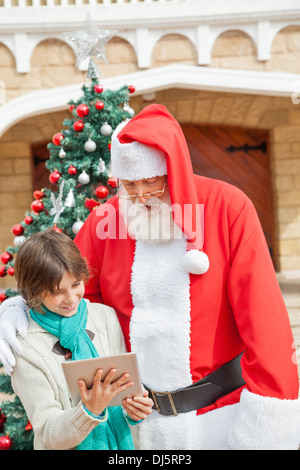 Santa Claus e Boy utilizzando tavoletta digitale Foto Stock